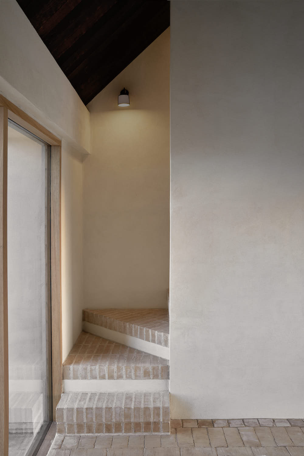 Staircase with lime wash walls and brick flooring.