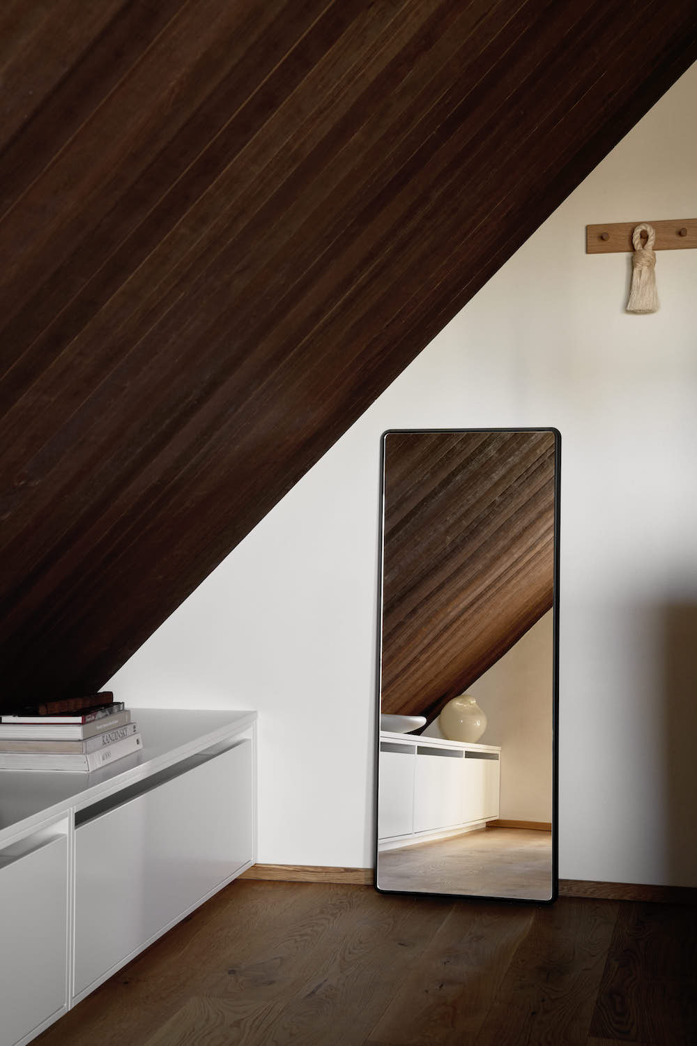 Mirror against a wall with low white cabinets.
