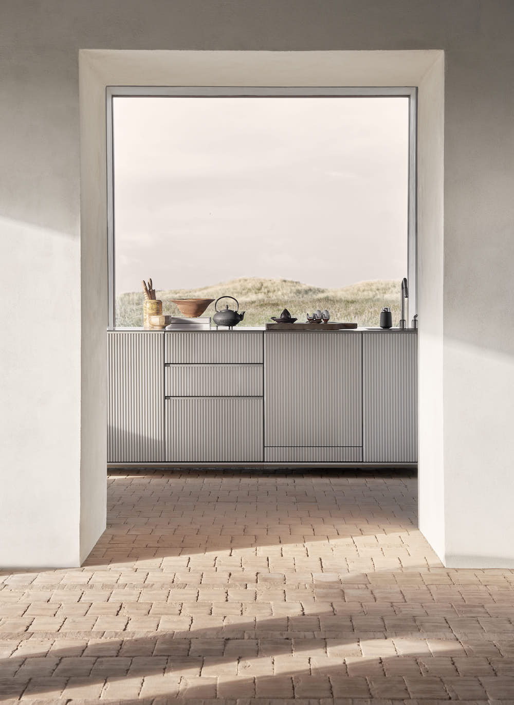 Aluminum kitchen in front of window with views over dunes.