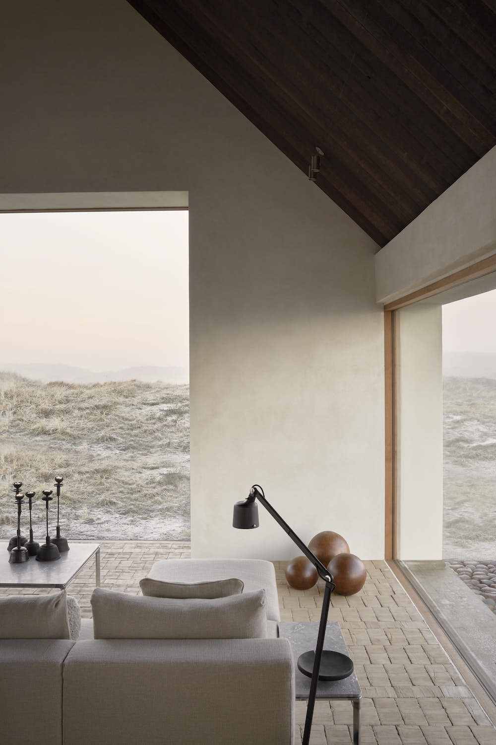 Corner of a living room with glass walls with views to the dunes.
