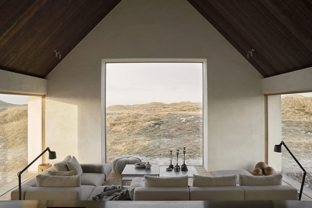 A living room with glass walls with views to the dunes.