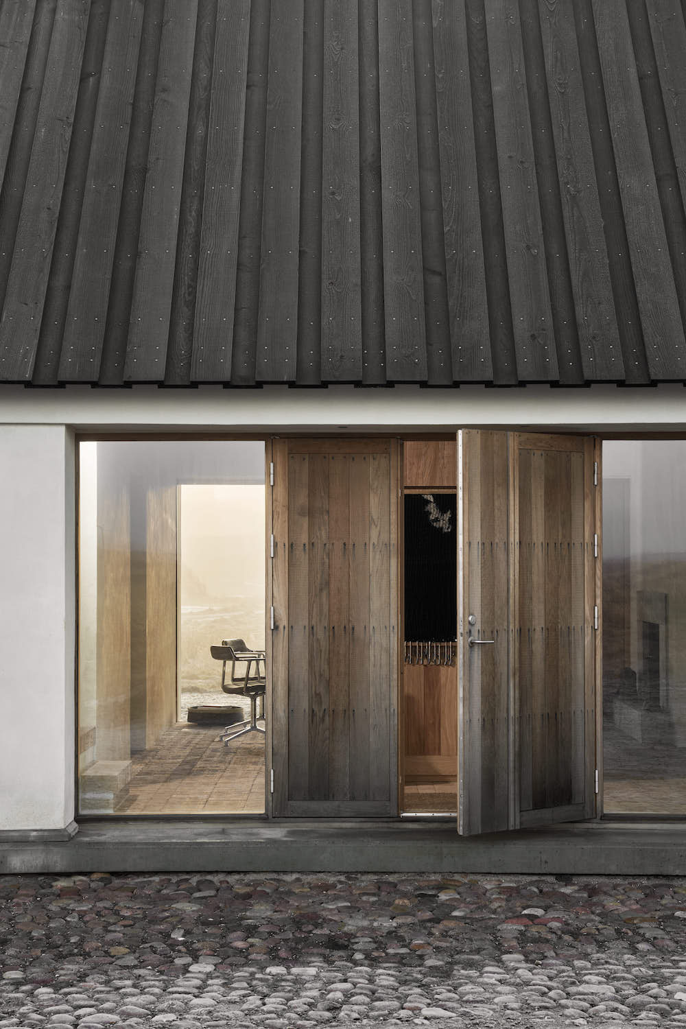A large wooden door to the house, flanked by glass walls.