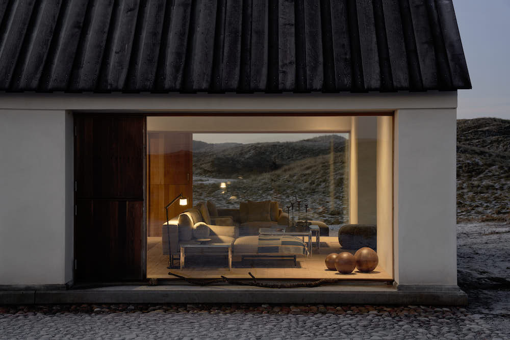 A peek through the living room glass wall reveals a stylish sofa, floor lamp and decoration.